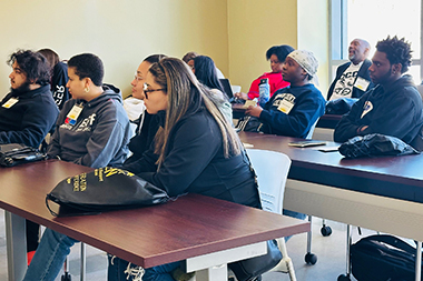 Students in a classroom taking notes and listening to the instructor.