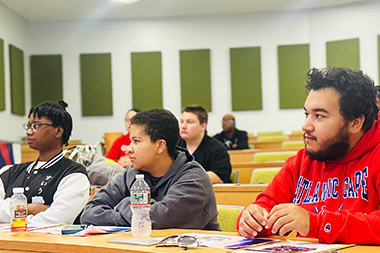 Students at a in a lecture hall listening to a presentation.