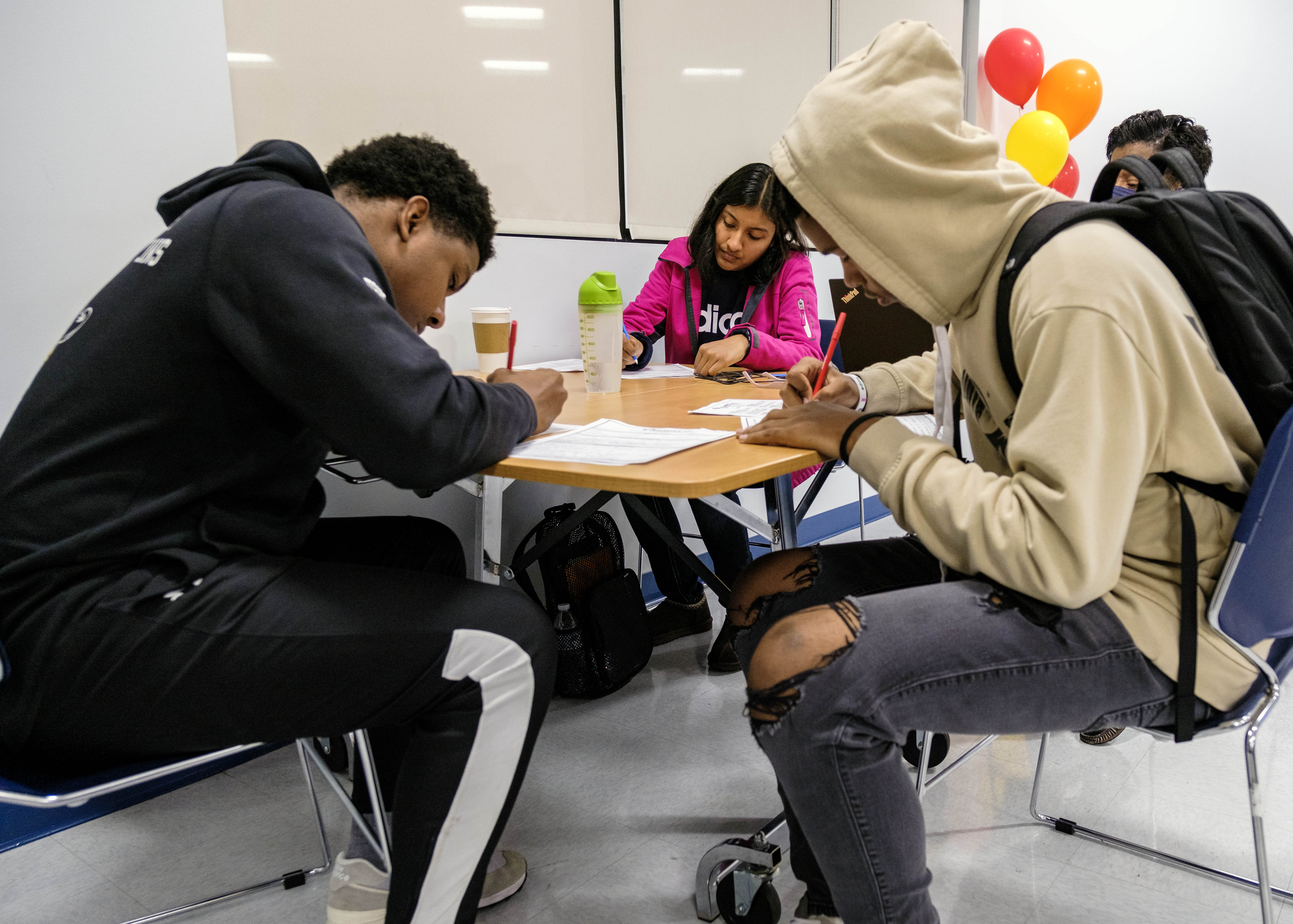 Three students completing paperwork at the same table.