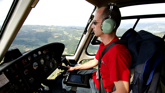 A man inside the cockpit flying a helicopter.