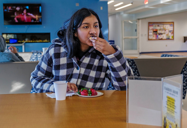 Student eating food while seated at a table.