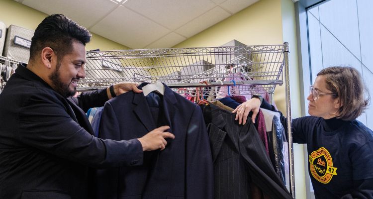 Victor Moreno and Leigh Chairman with the donated professional clothes in the Campus Closet