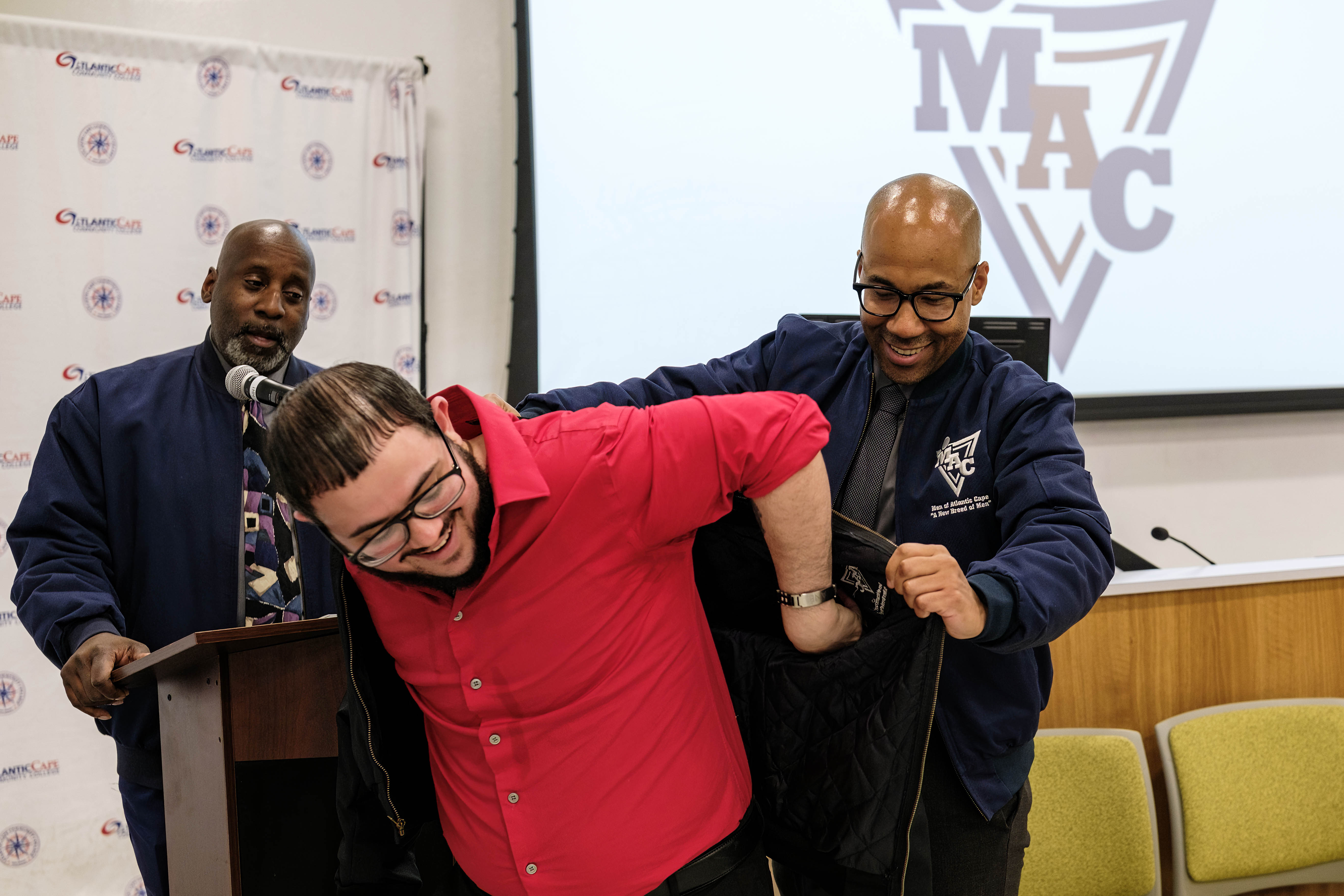Member student Alex Barr receives his MAC jacket from Jerome Ingram